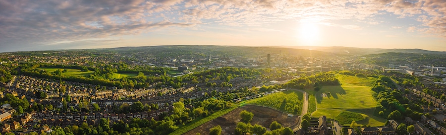 A panoramic view of a city with a river, green parks, and residential areas.