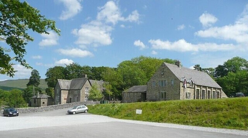 School and village hall, Cracoe The old school building is still in use, without any modern extensions. It has a belfry at the far end of the roof ridge. The sign on the grass bank reads 'caution change of surface'.