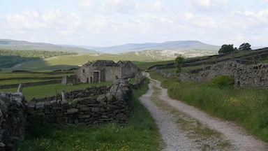 Un paysage rural avec des murs de pierre, un chemin de gravier et un bâtiment en pierre.