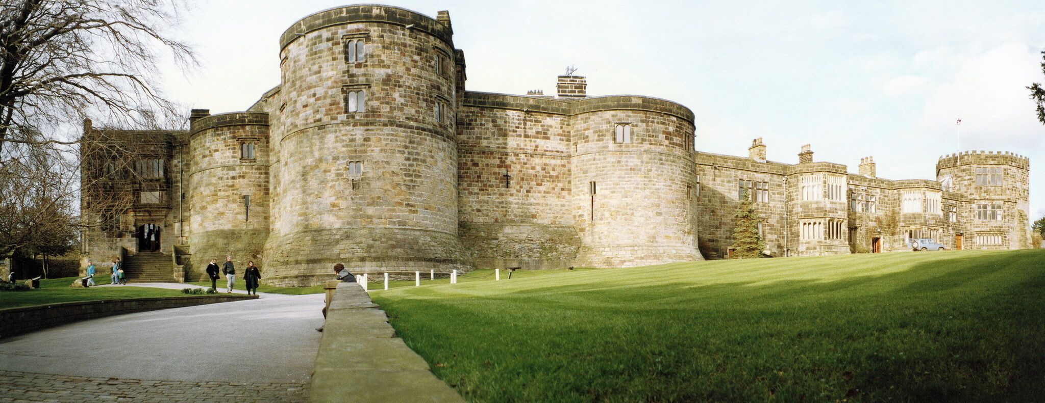 A large stone castle with multiple towers and a well-maintained lawn.