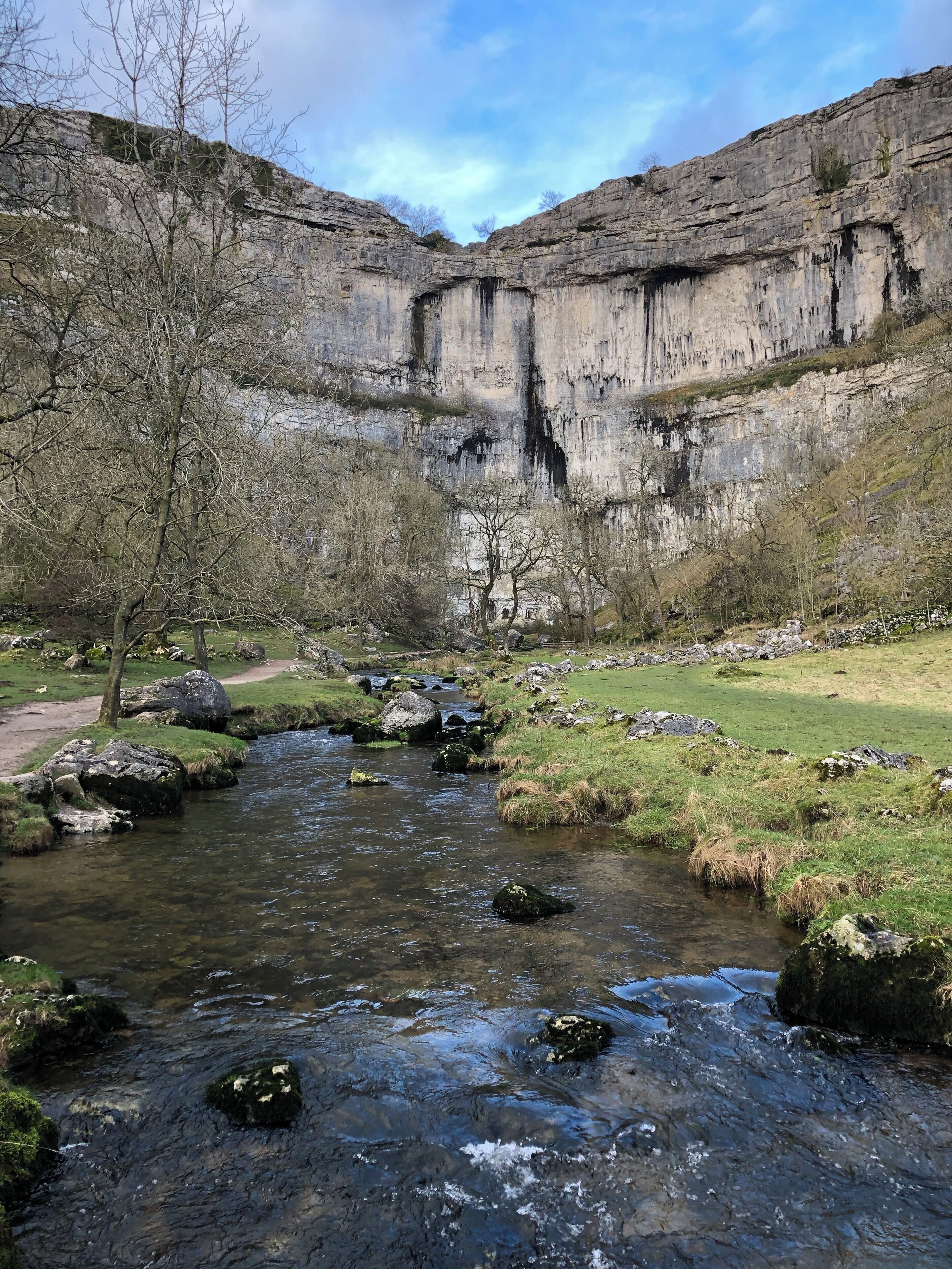 A river flowing through a valley with rocky cliffs and sparse trees.
