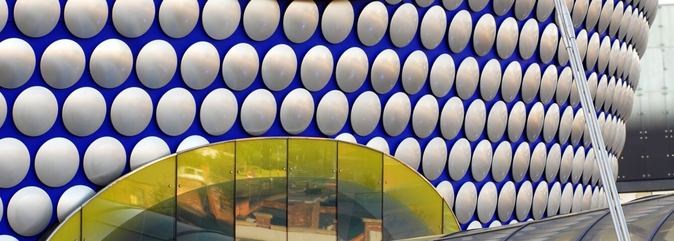 Un edificio con una estructura en forma de cúpula esférica y una pasarela con barandillas de vidrio.