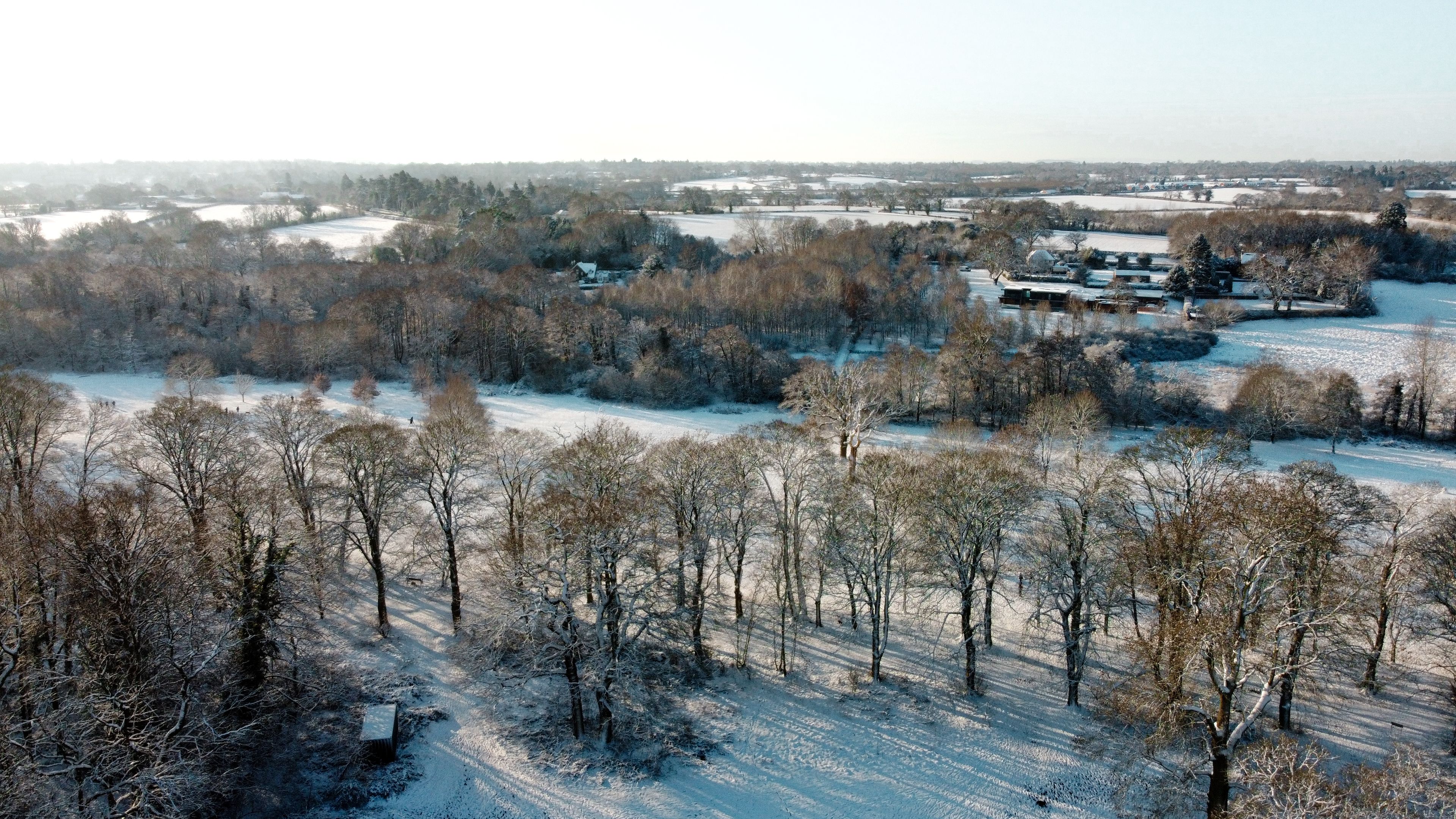 Aerial snow covered Solihull park and woodland scene, United Kingdom from drone