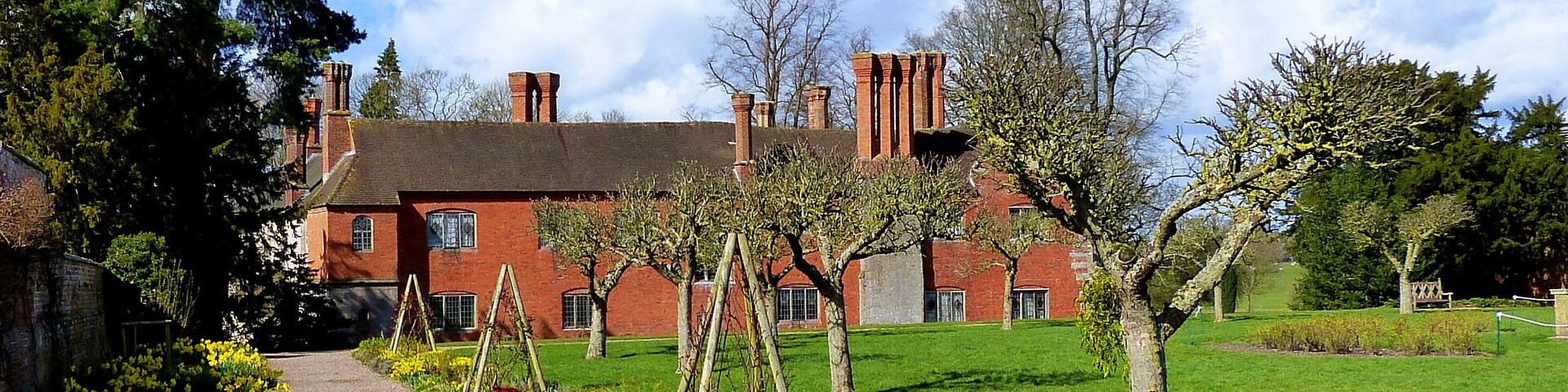 A red brick building with a green lawn and yellow flowers.