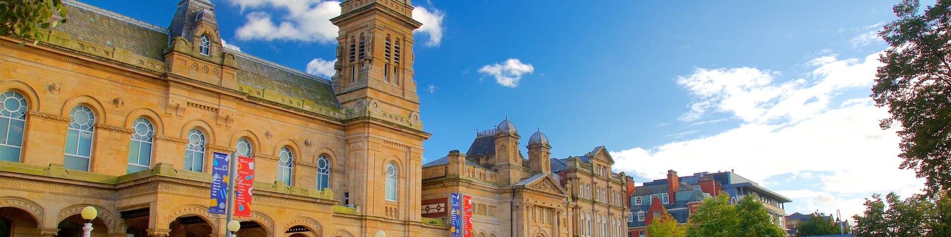 A historic building with a clock tower, arched windows, and banners.