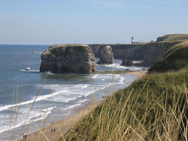 A coastal landscape with cliffs, waves, and a lighthouse.