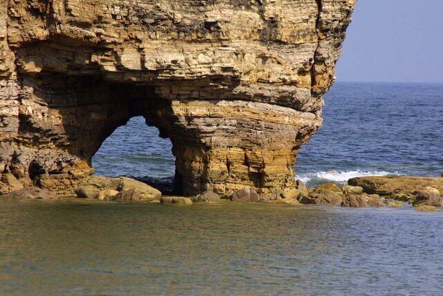 A coastal rock formation with a natural arch.