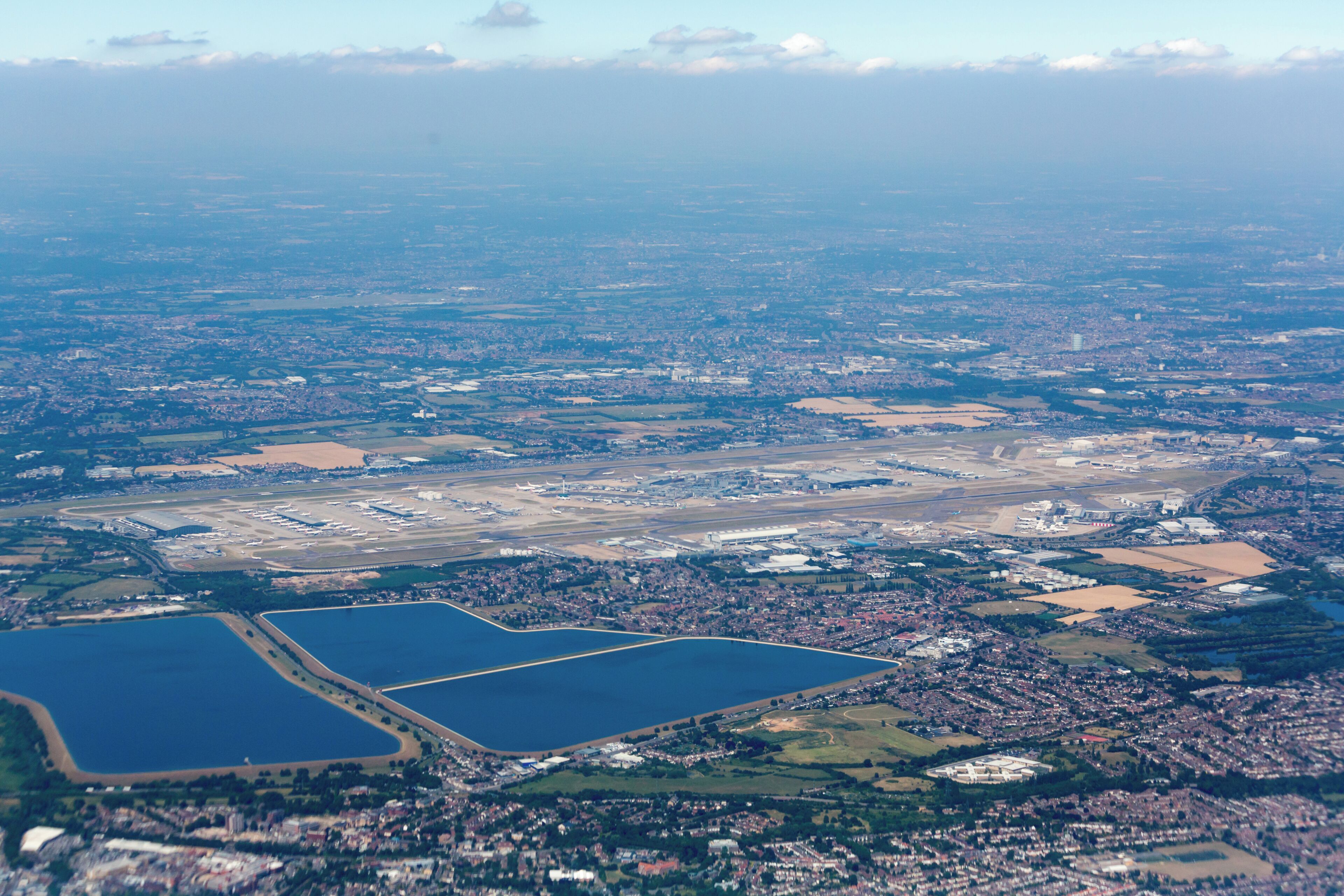 Aerial photograph of London taken on a Boeing 747-436 registration G-CIVG on departure from London Heathrow Airport (LHR/EGLL). Heathrow Airport is visible in the central foreground, with Staines Reservoirs under it, and King George VI Reservoir to its left.
