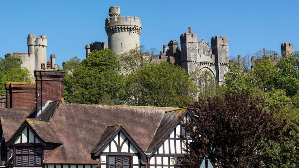 A historic castle with multiple towers and a church with a large arched entrance.