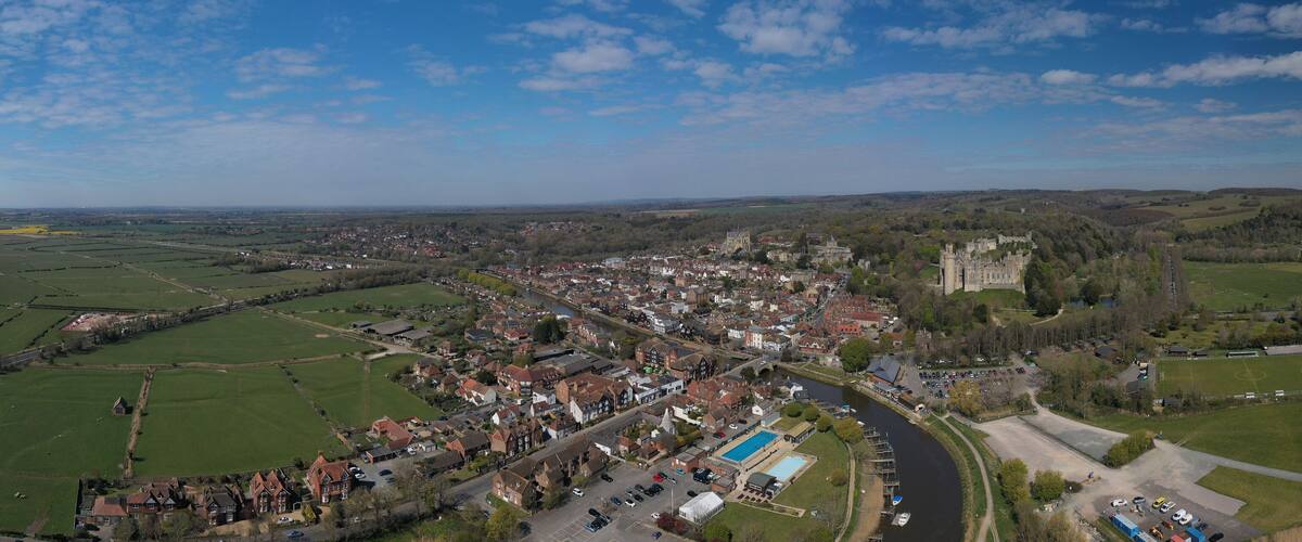 A town with a castle, green fields, and a river.