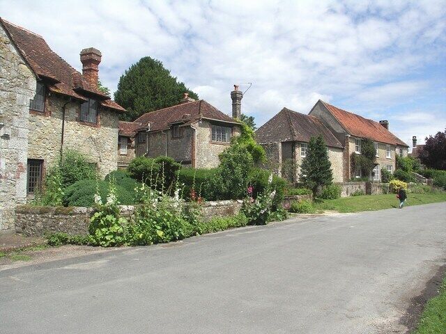 A rural street lined with stone houses, a clear sky, and lush greenery.