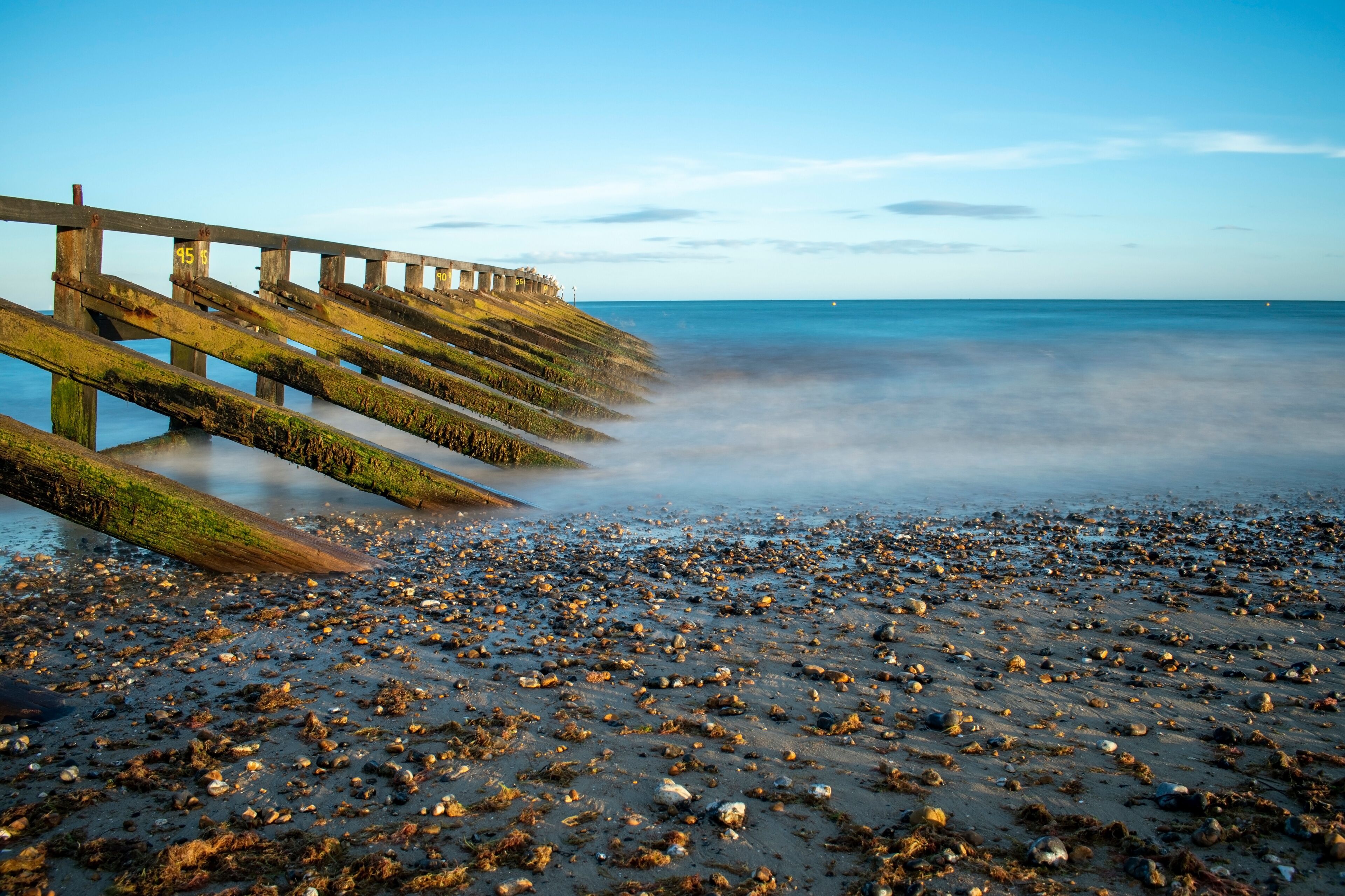 Calm and tranquil photo of the sea at west beach Littlehampton and the wooden sea defence for the River Arun.