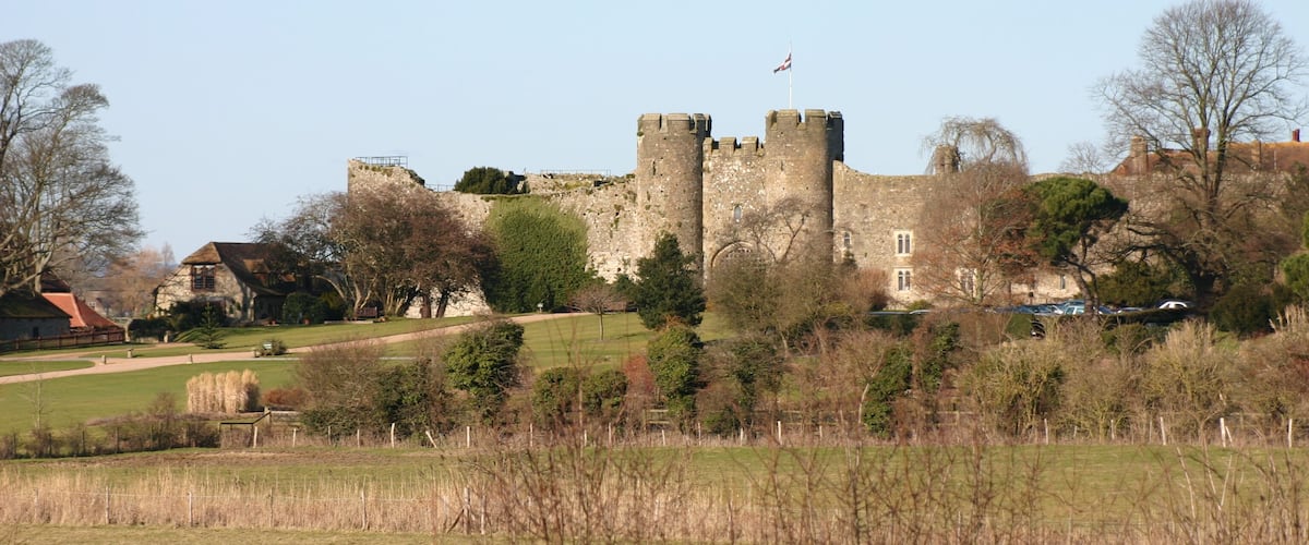 A historic castle with multiple towers, surrounded by trees and a grassy field.