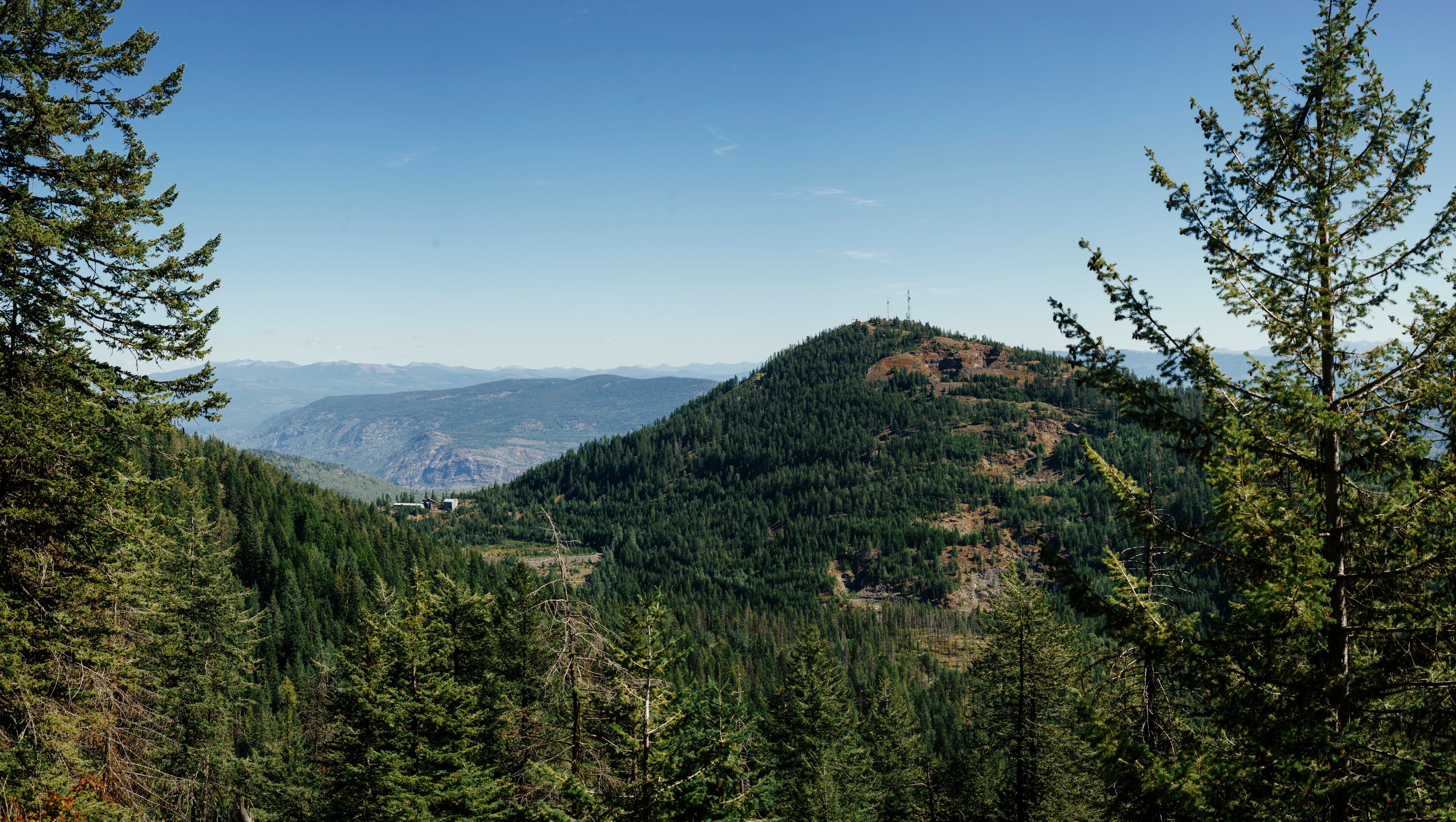 A mountainous landscape with dense forests and a clear sky.