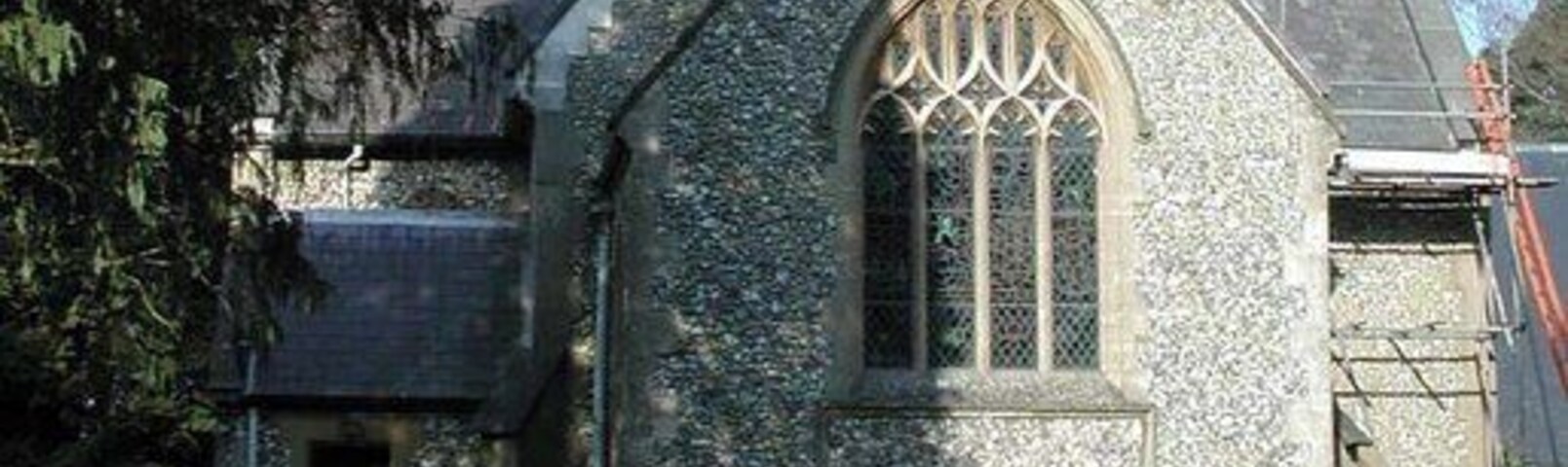 Una iglesia de piedra con techo puntiagudo y un amplio ventanal de arco.