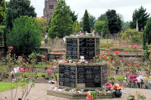 One of the cremation Memorials at Stockport Cemetery St. George's Church, can be seen through the trees.