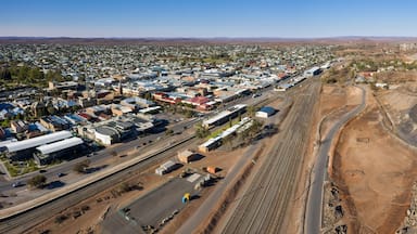 An aerial view of a town with a railway track, a large open excavation site, and distant hills.