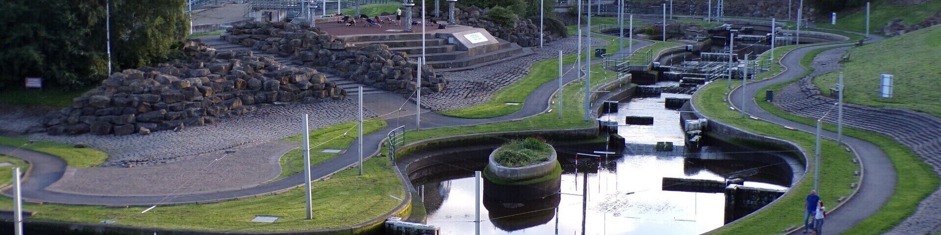 Um parque com lago, uma ponte e um edifício grande com cúpula.