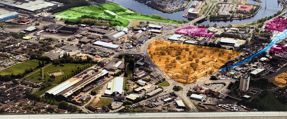 An aerial view of a town with a river, industrial buildings, and a bridge.