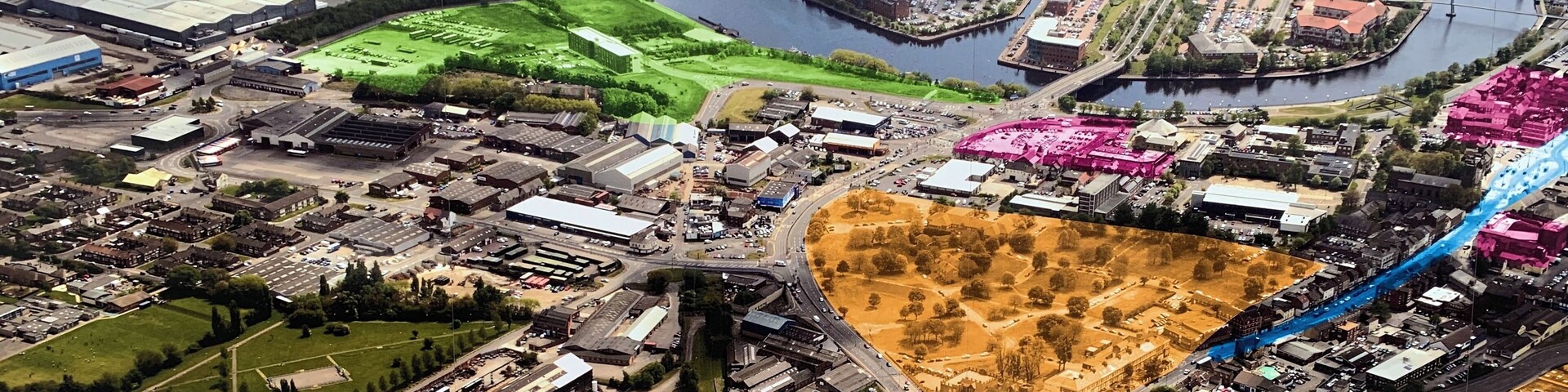 An aerial view of a town with a river, industrial buildings, and a bridge.