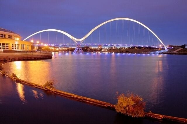 A bridge with two arches over a body of water at night.