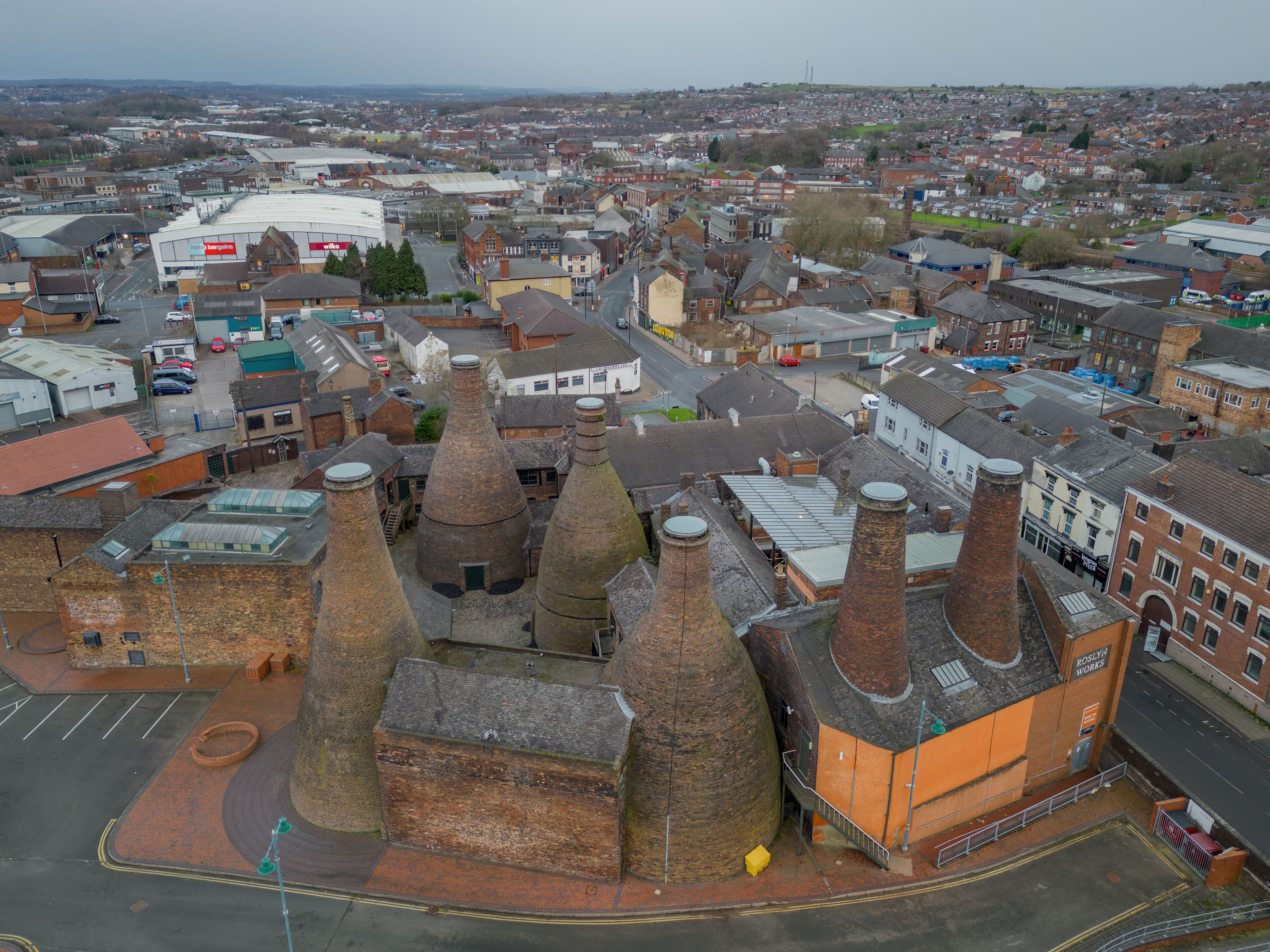 An aerial view of a town with distinctive brick buildings and several conical structures.
