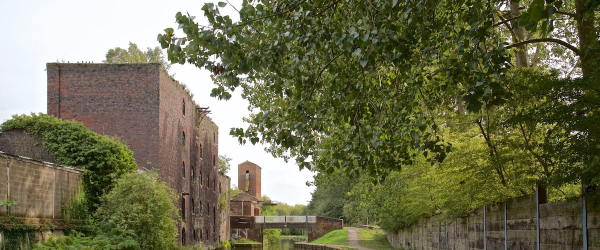 A narrow canal with a brick building and a bridge.