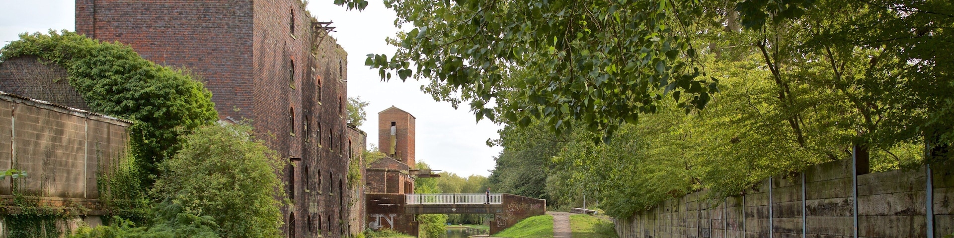 A narrow canal with a brick building and a bridge.