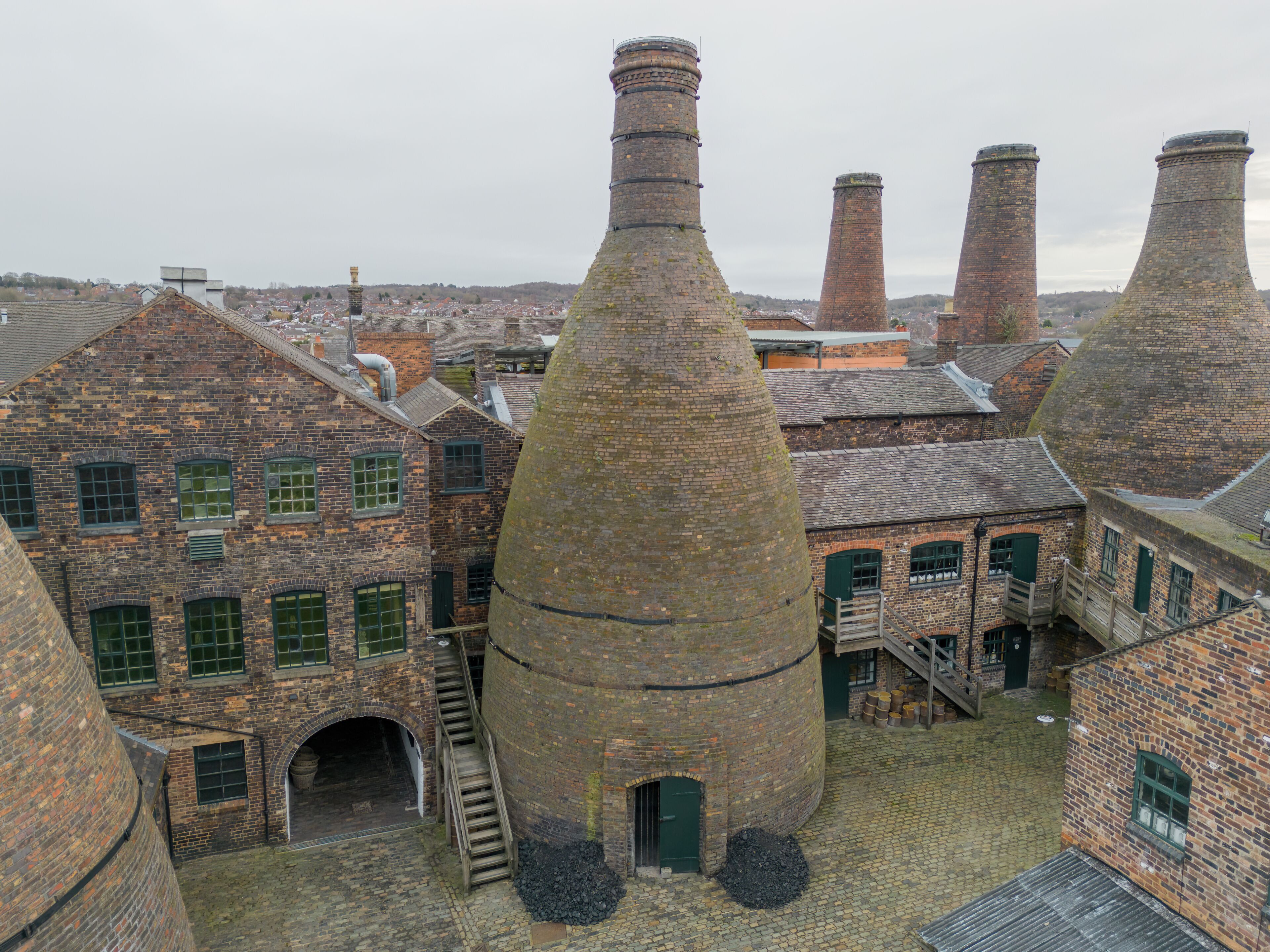 A historic industrial complex with brick buildings and large cylindrical chimneys.
