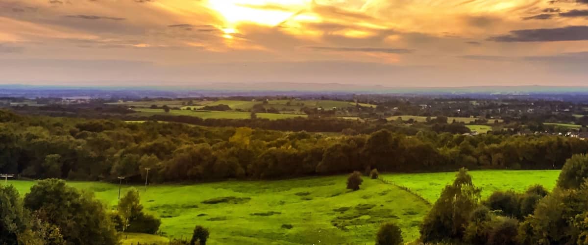 A sunset over a green landscape with a clear sky.