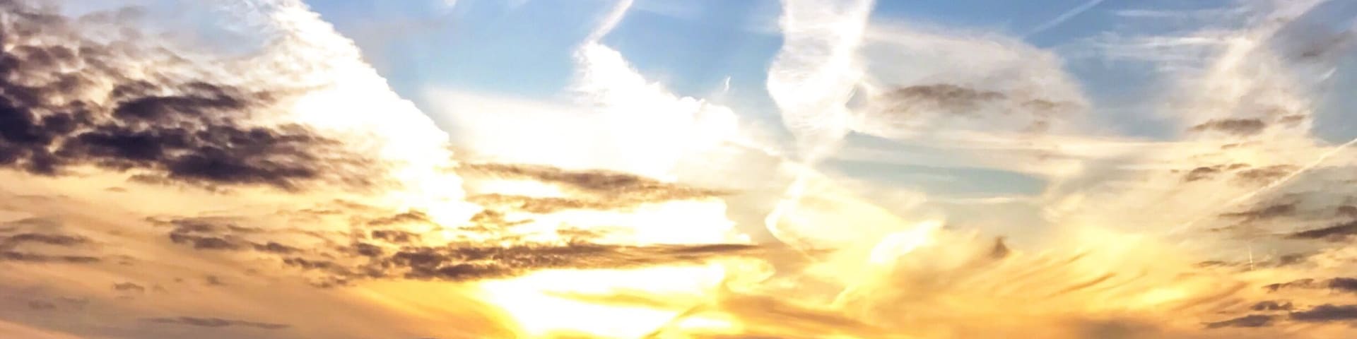 A sunset over a green landscape with a clear sky.