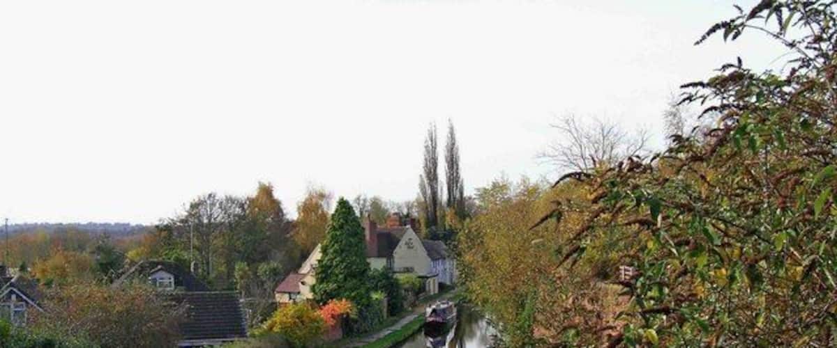 Un canal estrecho flanqueado por casas a un lado y árboles al otro.