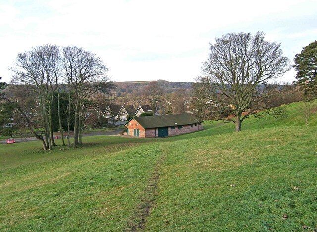 Um campo gramado com um pequeno edifício e árvores.