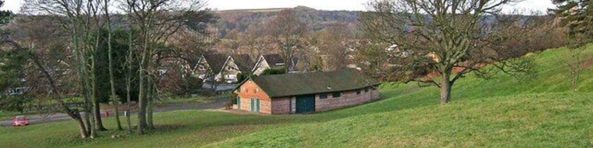 Um campo gramado com um pequeno edifício e árvores.