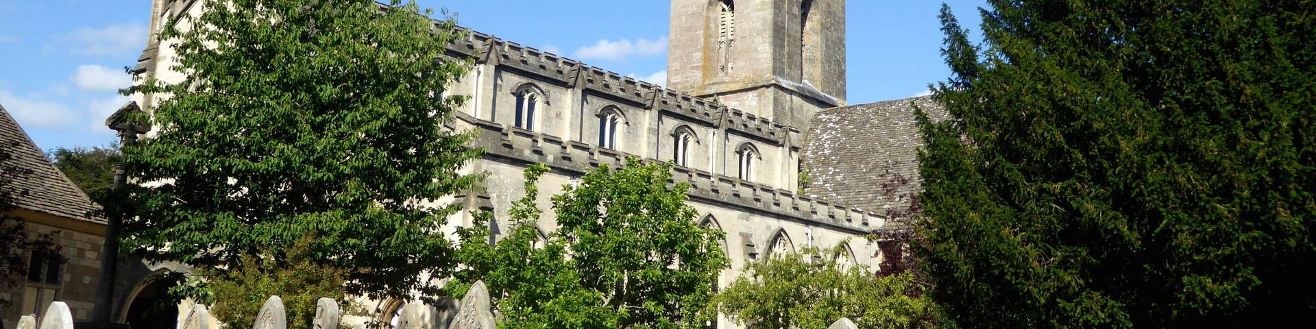 A historic church with a tall tower and a stone wall in the foreground.