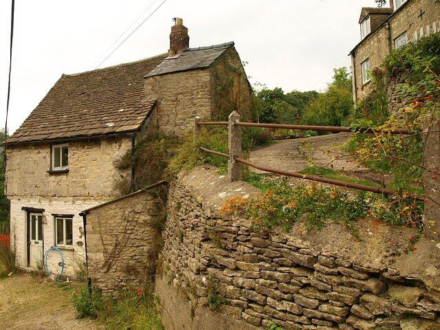 A stone house with a wooden fence and a stone wall.