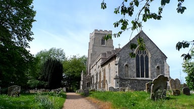 A church with a stone tower and a graveyard with headstones.