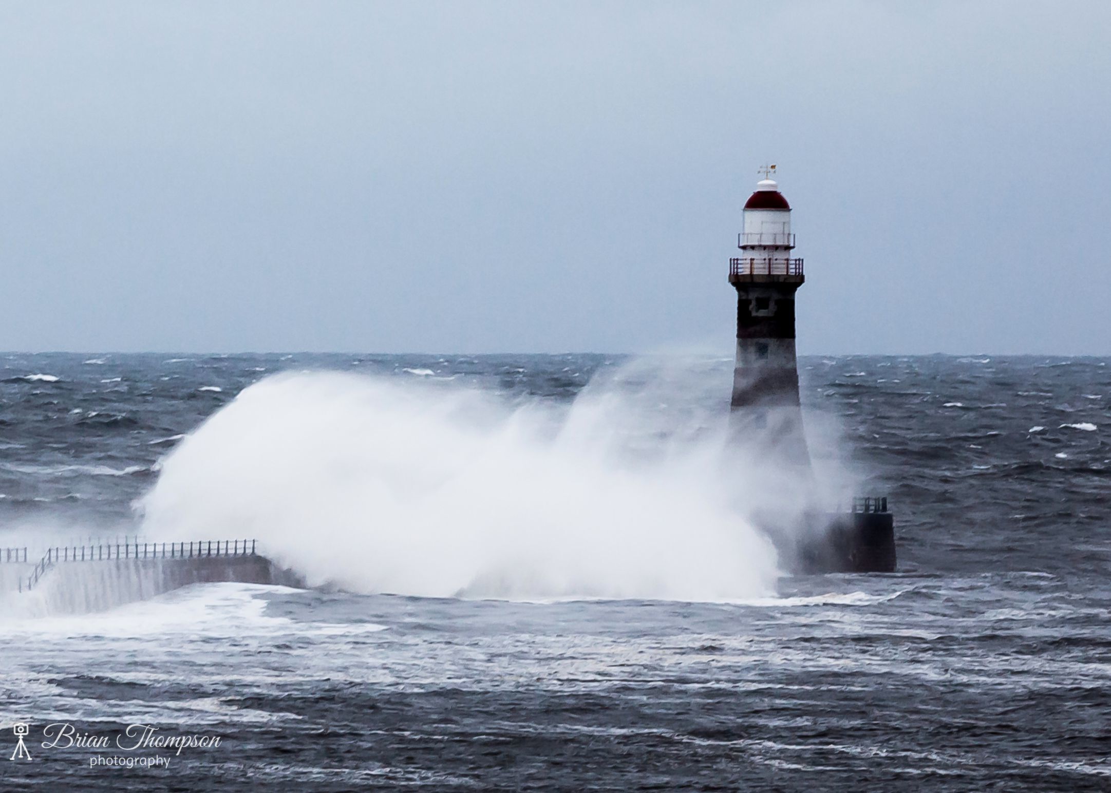 A lighthouse with waves crashing against it.