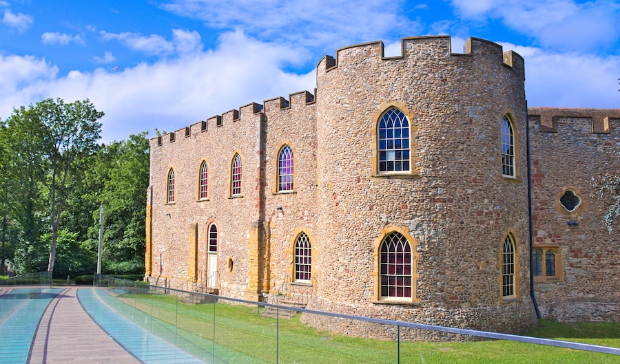 Taunton castle, Somerset Museum, England, Uk. Bright summer morning with blue sky and some clouds, green meadow and trees, glazed walkway