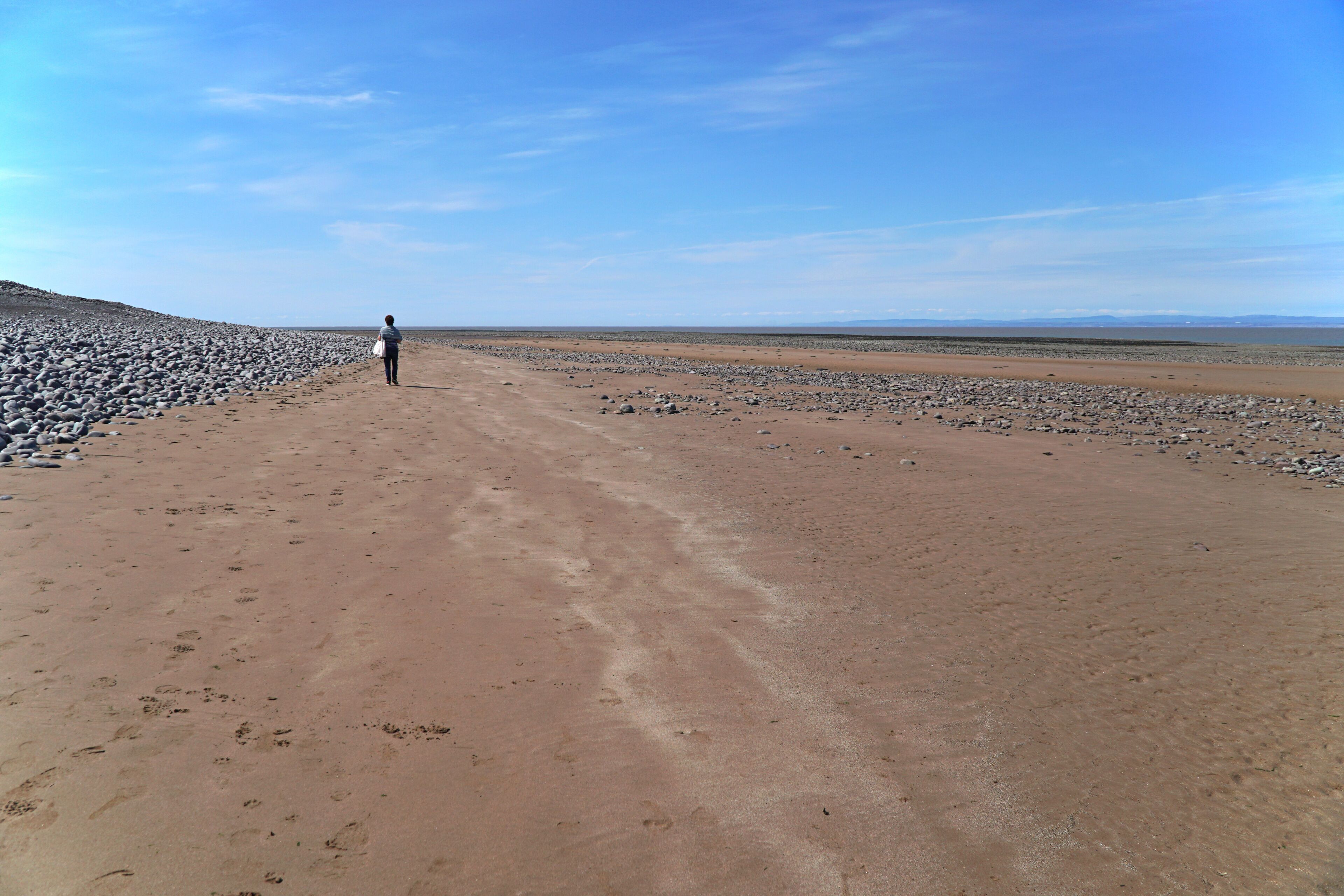 A vast desert landscape with a person walking on a dirt path.