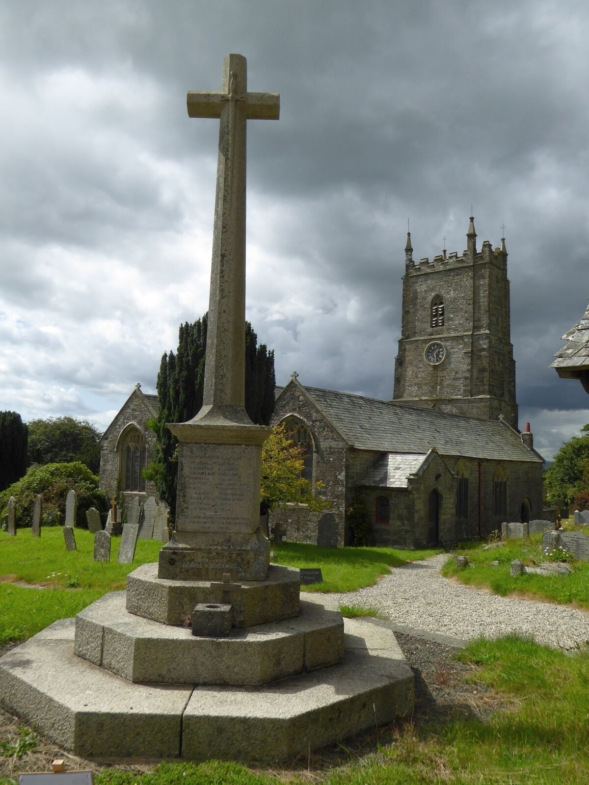 A church with a tall tower and a large cross in the foreground.