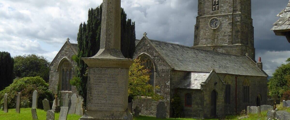 A church with a tall tower and a large cross in the foreground.