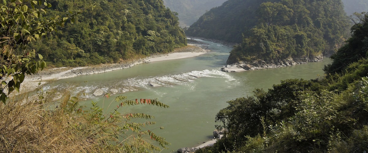 A river winding through a mountainous landscape with dense greenery and rocky riverbanks.