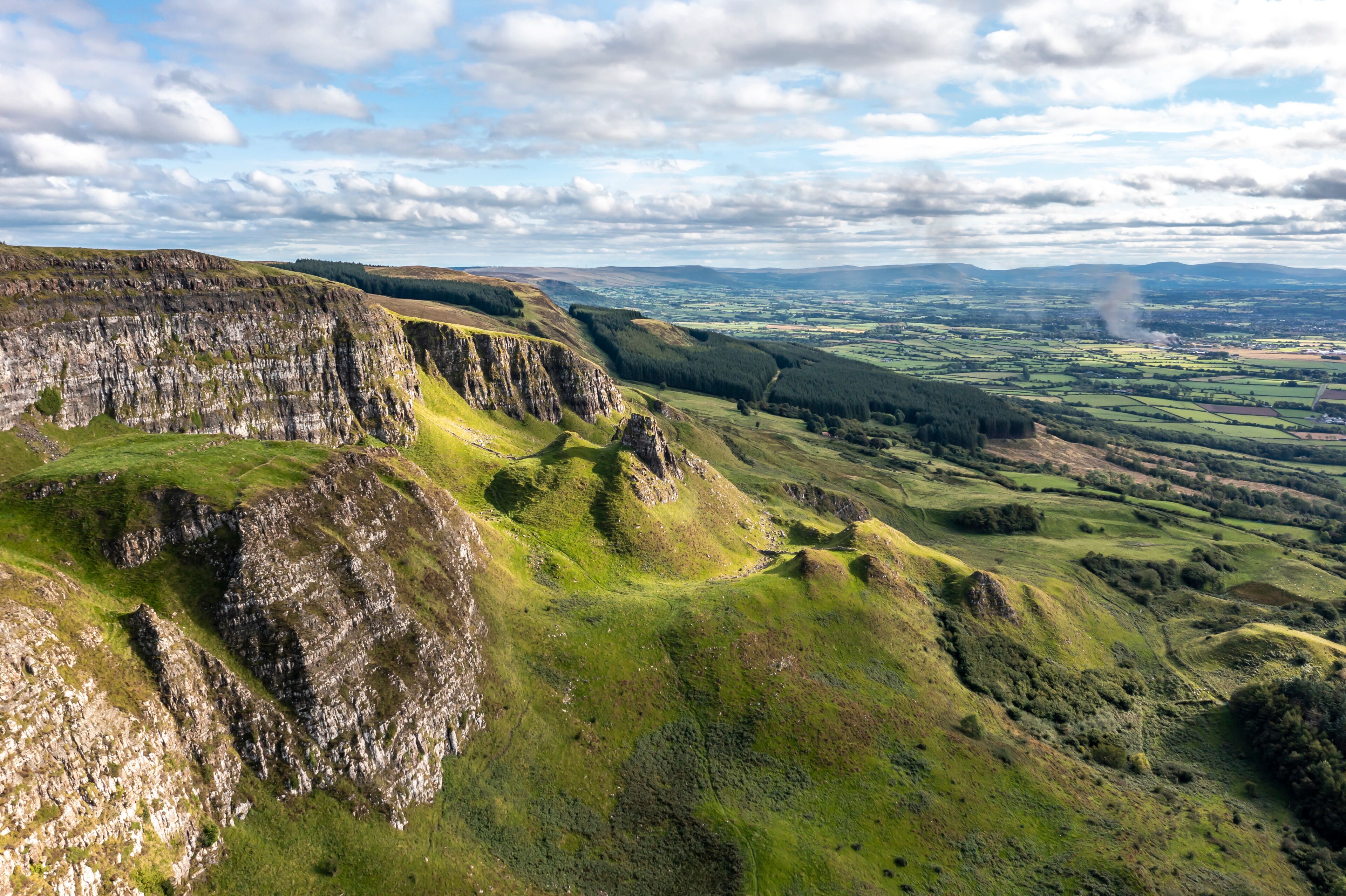 Paisagem acidentada com penhascos íngremes e colinas ondulantes.
