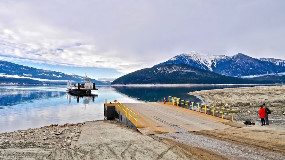 Un lac paisible, avec un quai, un bateau et, au loin, des montagnes aux sommets enneigés.