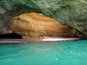 Eingang einer Höhle mit türkisblauem Wasser.