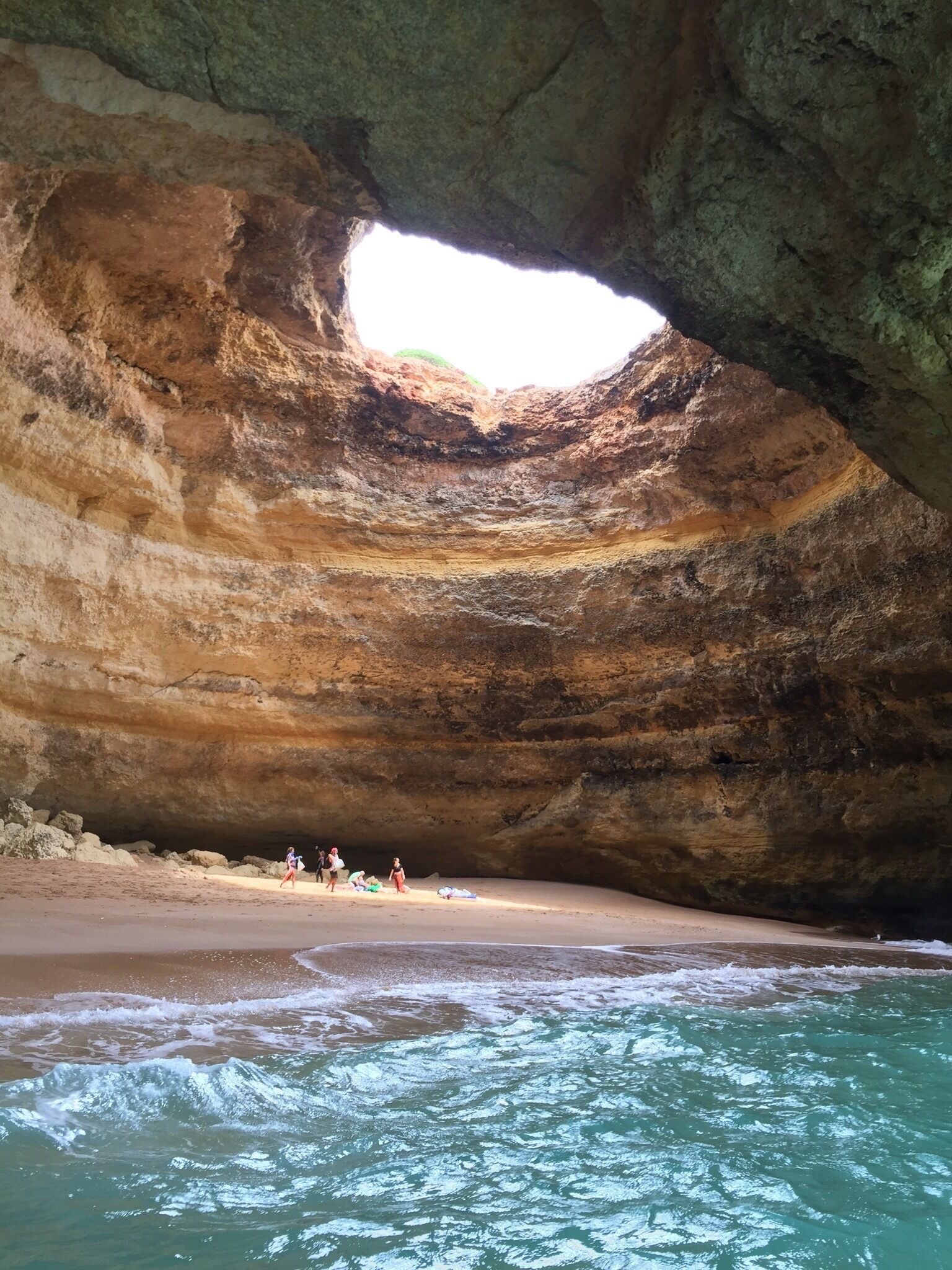 A natural rock formation with a cave opening to a beach.