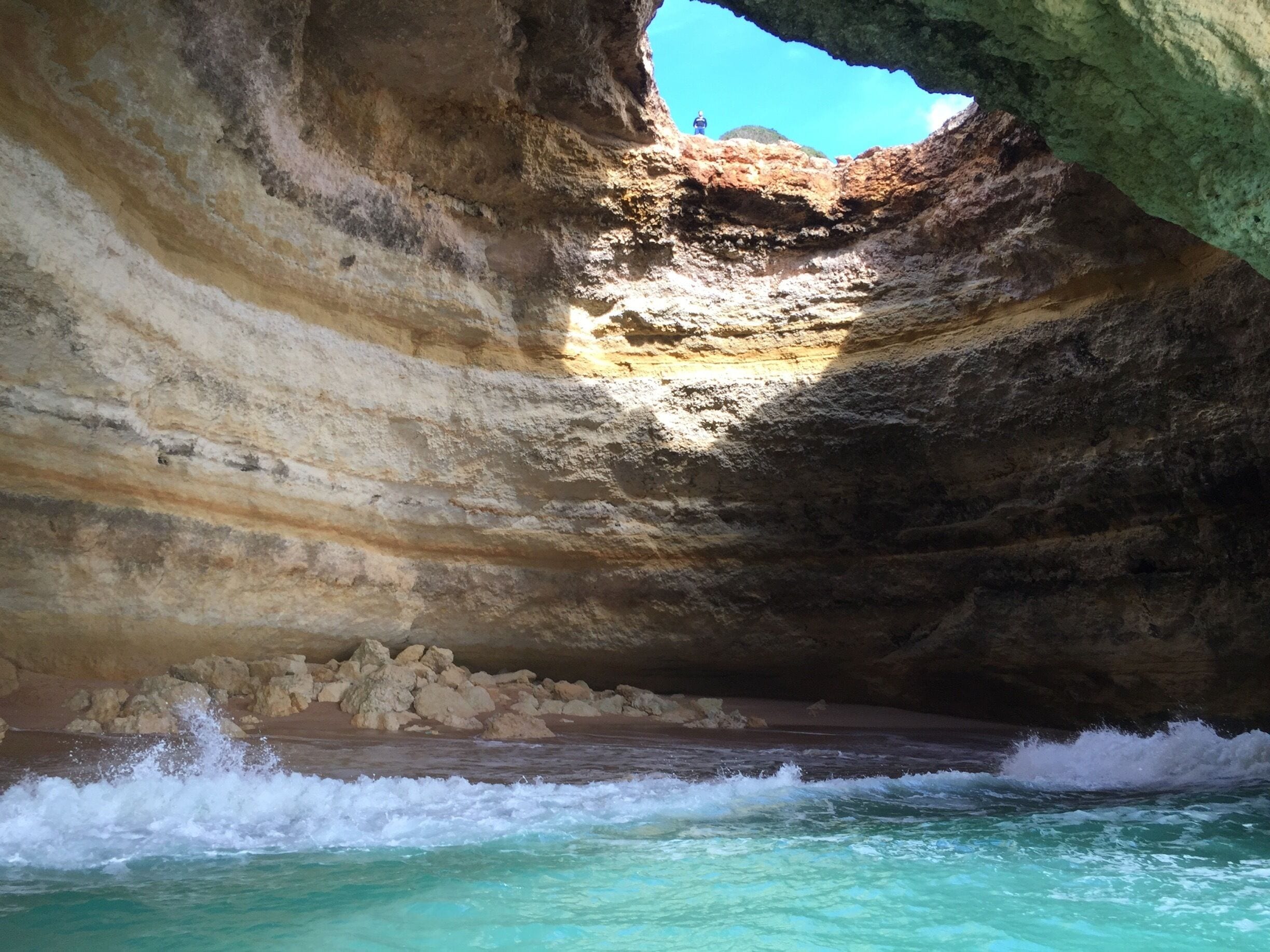 A cave with a view of the ocean through a natural arch.