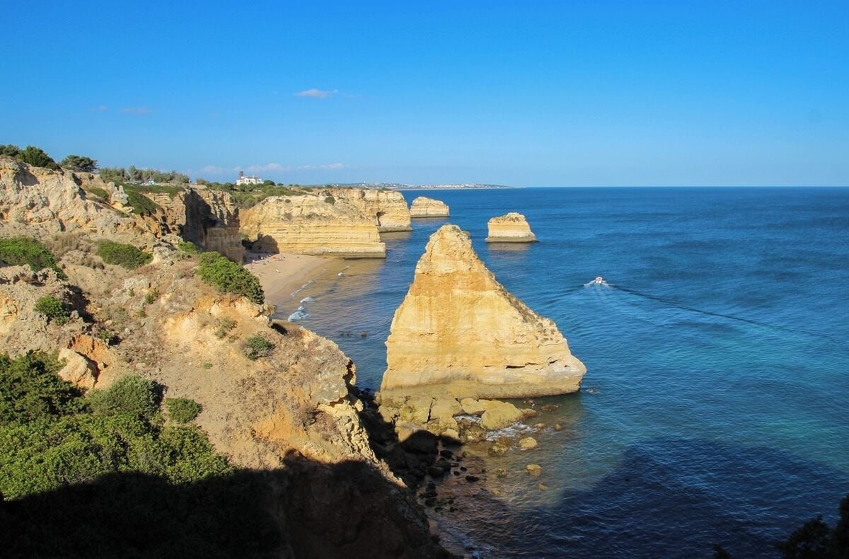 A coastal landscape with prominent rock formations and a clear blue sea.