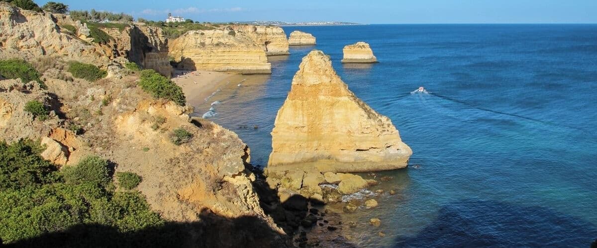 A coastal landscape with prominent rock formations and a clear blue sea.